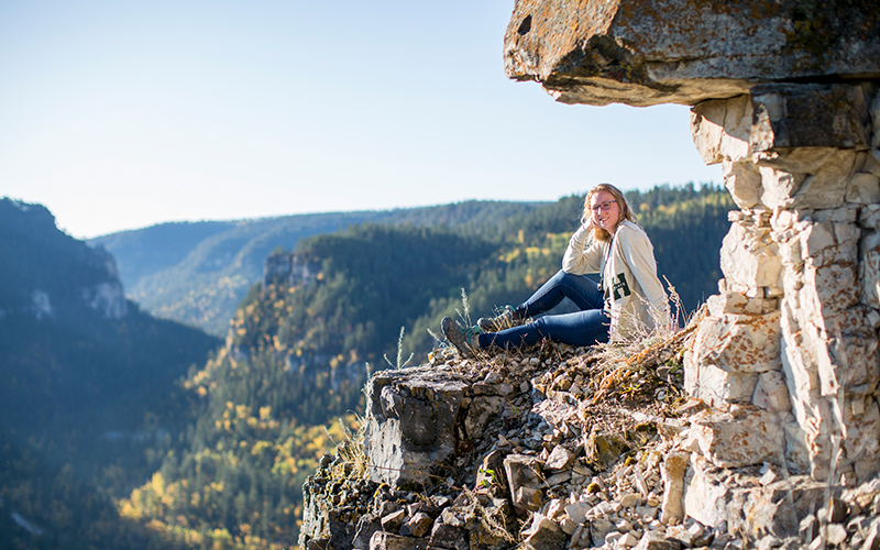 A student poses for a photo on a cliff.