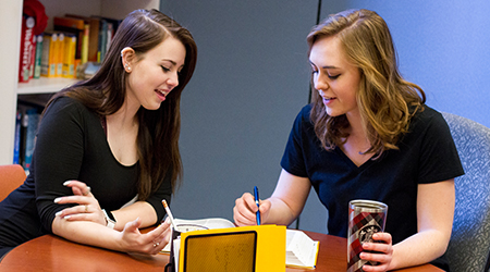 Two women sit at a table together.