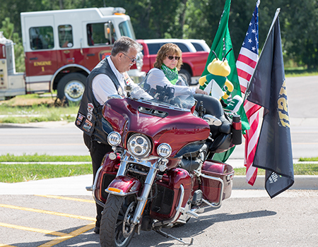 Two Rally goers stand with their motorcycle.