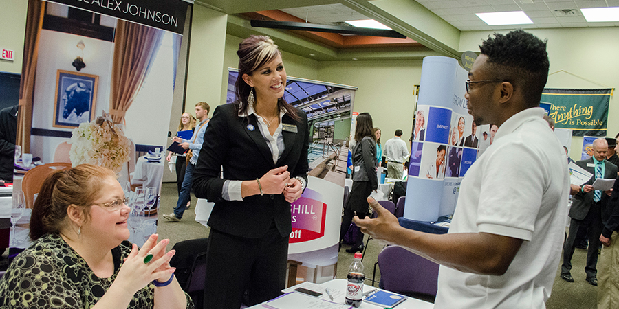 A student on the right speaks to two advisors.