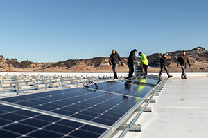 Five guys installing solar panels on the roof of a building