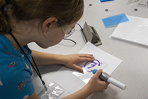 Child helping with a STEM project and writing on a piece of paper