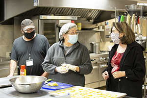 Augustine Rosales, Lisa Tognotti, and Lysa Allison preparing food in the kitchen