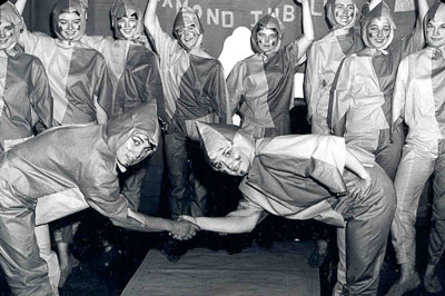 Two people in costume shake hands at a 1965 BHSU Homecoming event.