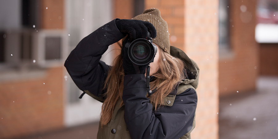 Woman aims a camera towards the camera.