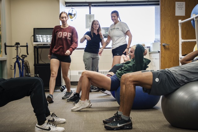 Exercise Science students and instructor in a laboratory classroom setting discussing physical therapy techniques