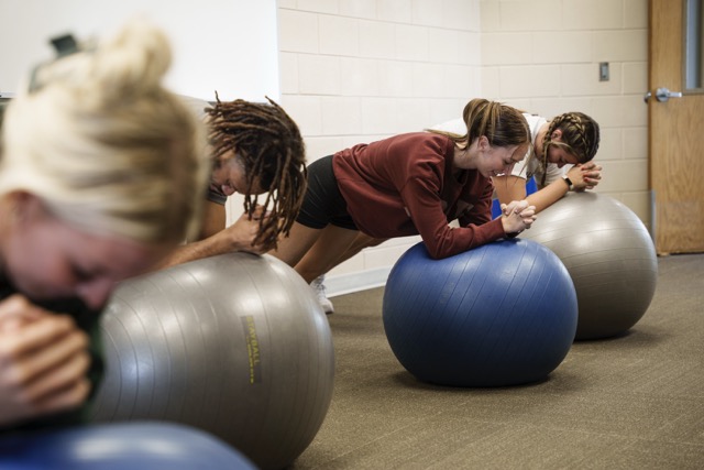 Students practicing stability exercises on exercise balls during a core training session in the Exercise Science lab