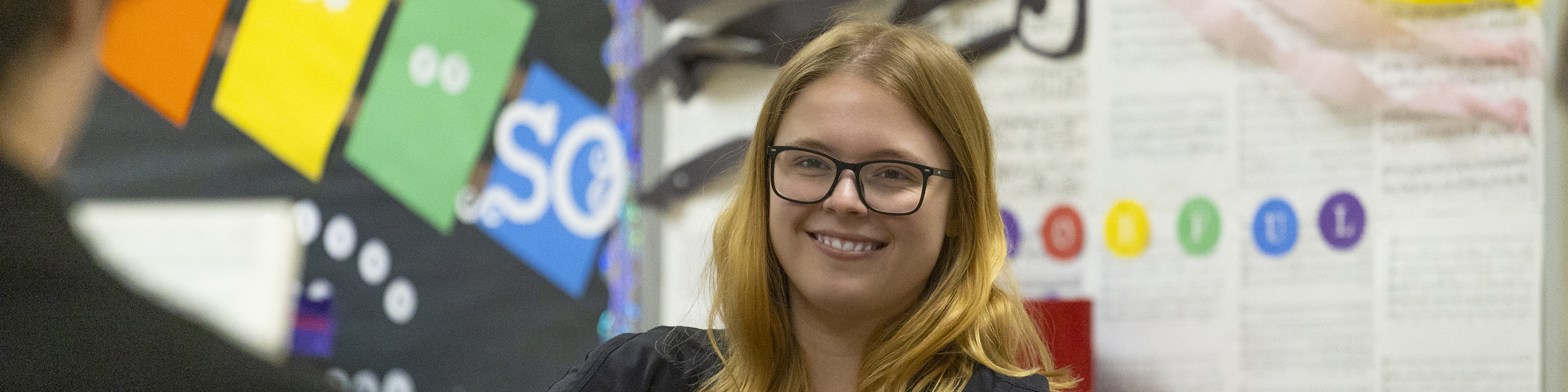 girl sitting in a music classroom smiling at the camera