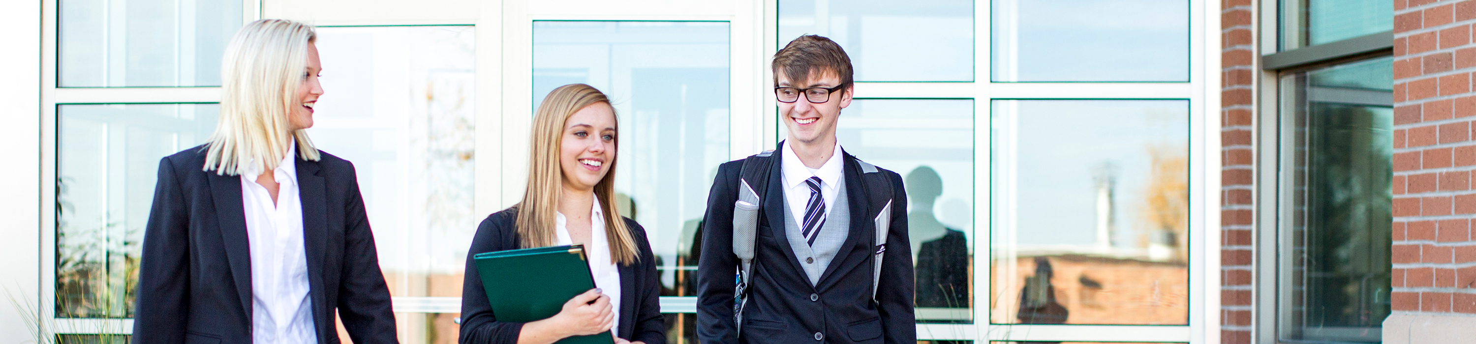 Three business administration degree seeking students exiting an on-campus building.