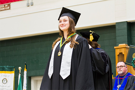 A female honors graduate receives her honors medal at graduation.