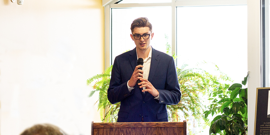 Man talks with a microphone at a podium.