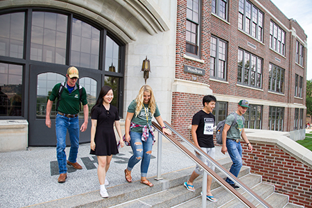 Five students walk down the stairs outside Woodburn Hall.