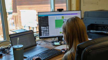 Woman sitting at a desk looking at a computer screen.