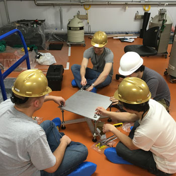Group of four REU students sitting on the floor working on a project together.