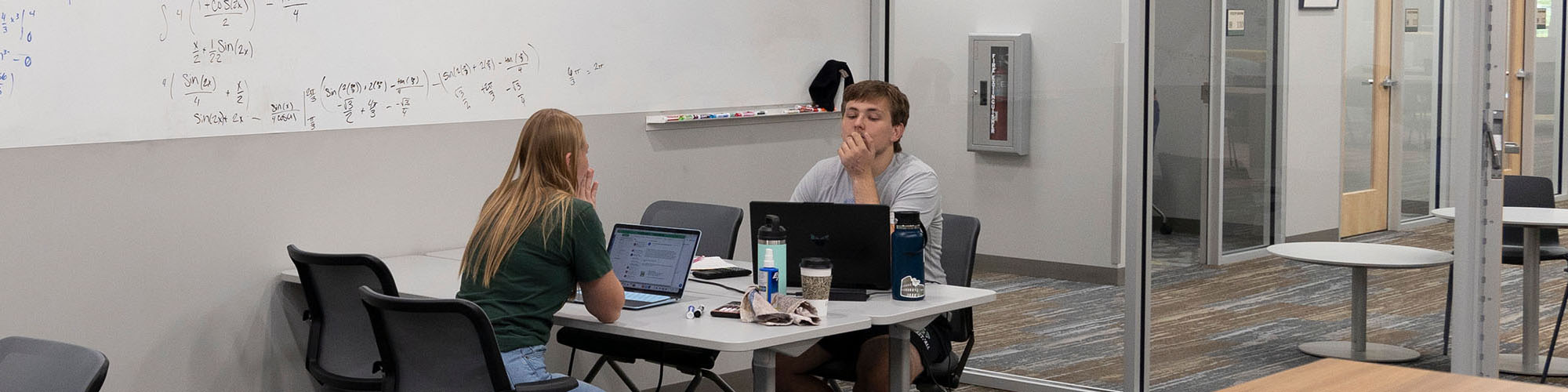 A mentor sits across from a student, preparing to work together on math equations.