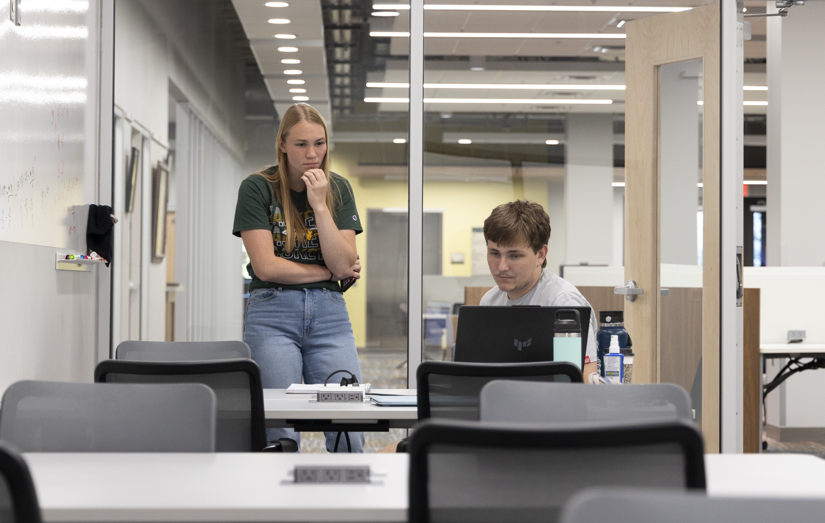 A mentor standing on the left and a student sitting on the right work together to solve math equations.