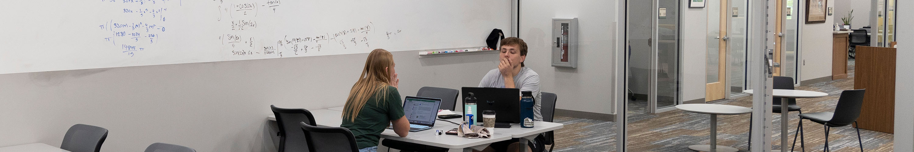 A mentor sits across from a student, preparing to work together on math equations.