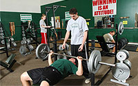 BHSU Young Center members working out in the weight room; man working on the bench with spotter