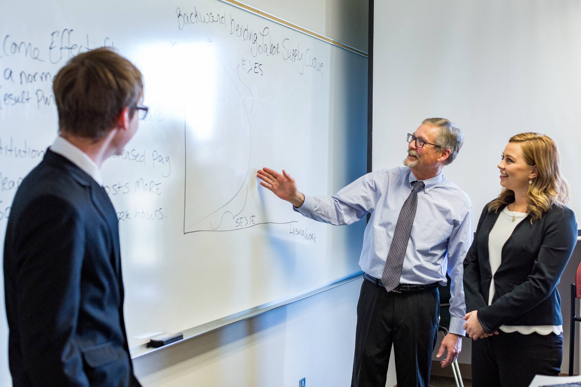 Image of BHSU students in a business classroom with a professor. They are all dressed professionally.