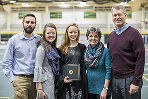 BHSU graduate holding diploma with family 