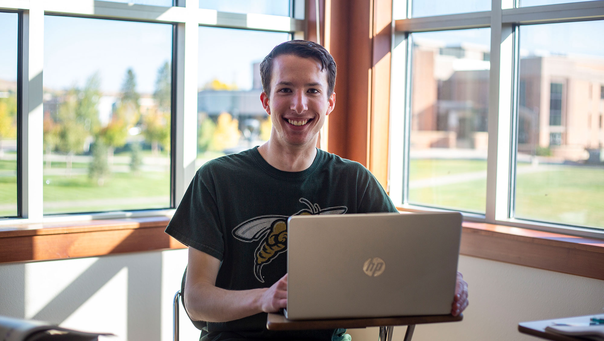 BHSU student smiling while sitting at a table with a laptop.