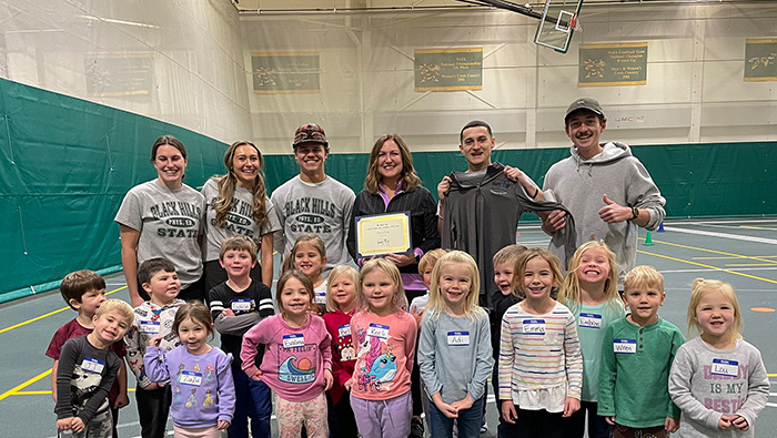 Dr. Breon Darby holding award with BHSU Students and Preschool class.
