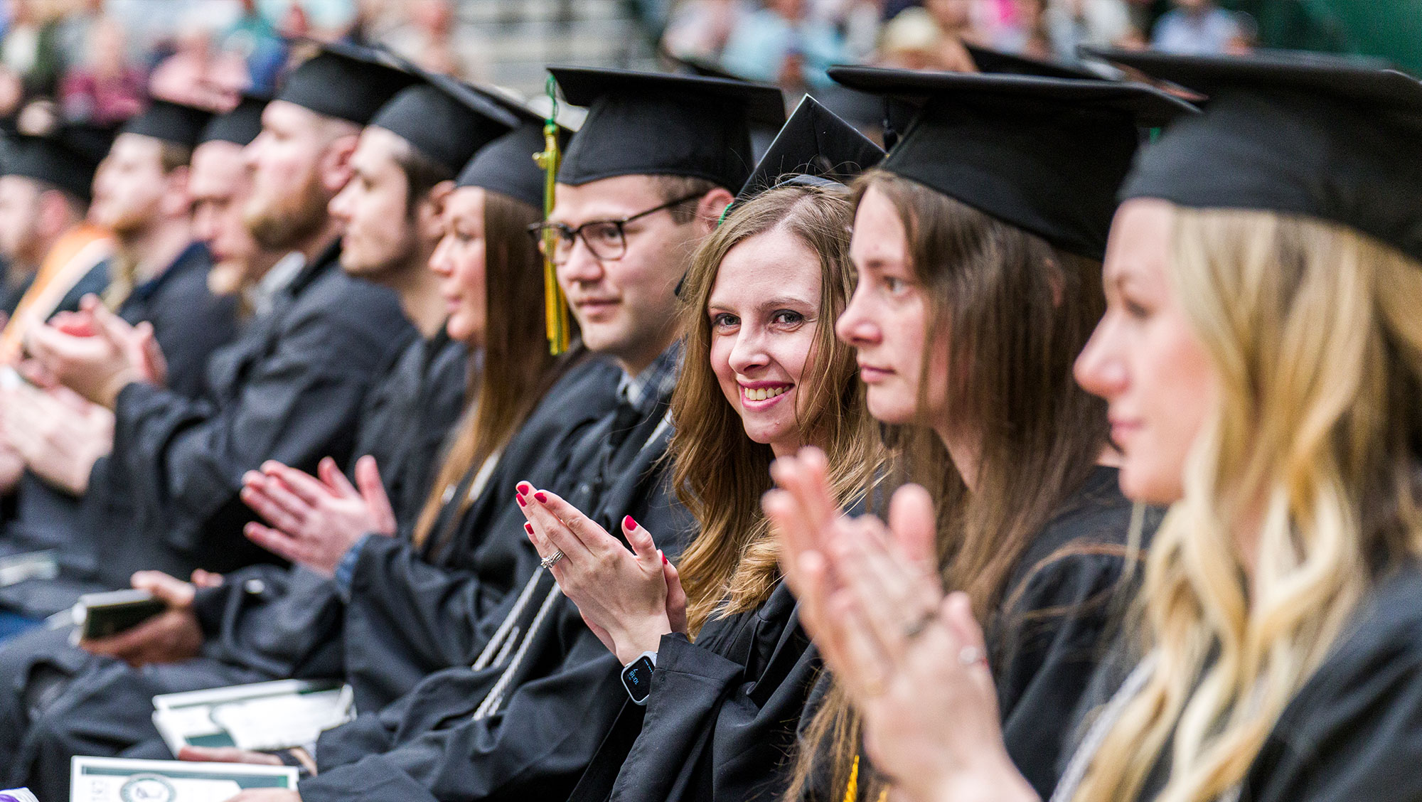 BHSU students dressed in caps and gowns sit in a row during fall graduation