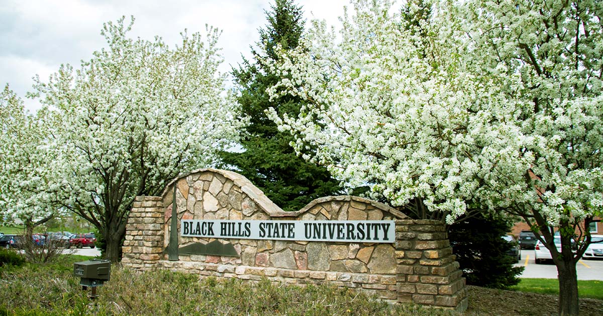 Trees with white flowers frame BHSU sign