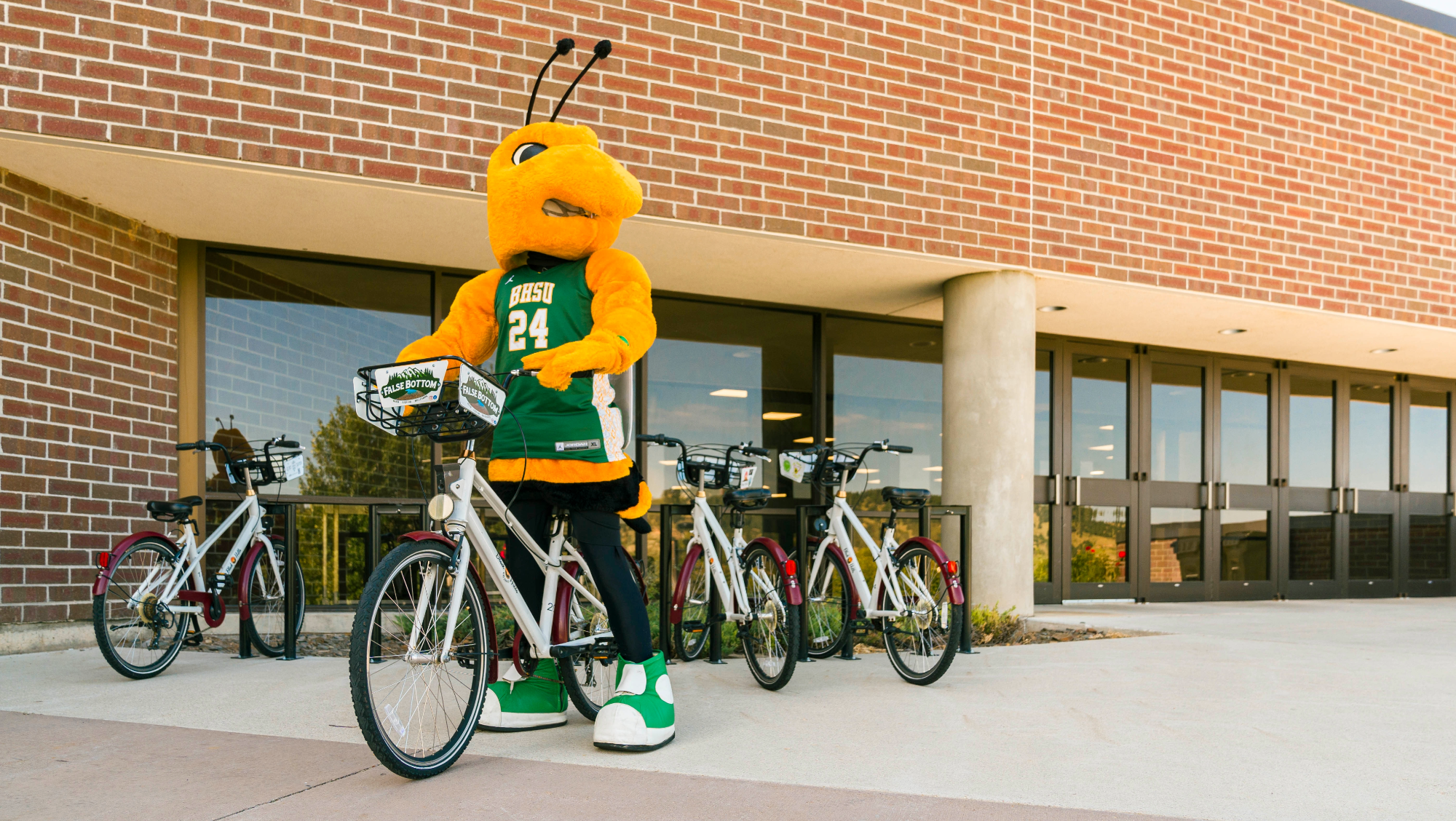 BHSU mascot, Sting, riding a bike in front of the Young Center