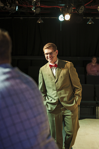 man dressed in a tan suit smiling and walking towards the camera