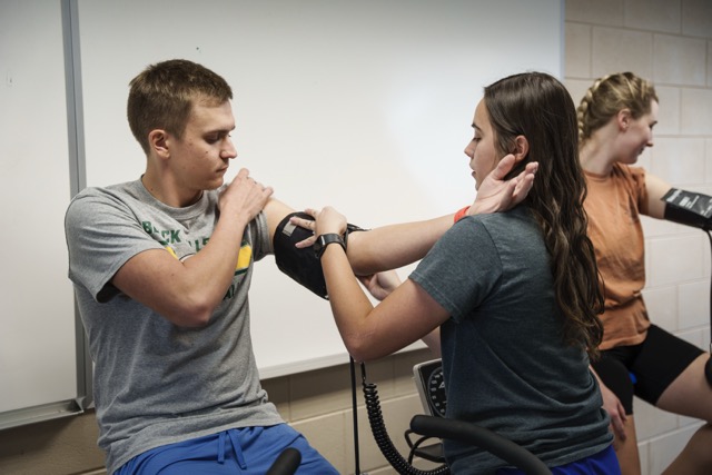 Exercise Science instructor conducting a biomechanical assessment on a student's arm mobility in the laboratory setting
