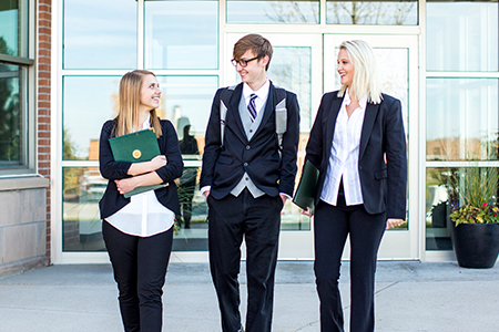 Three business students walk together.