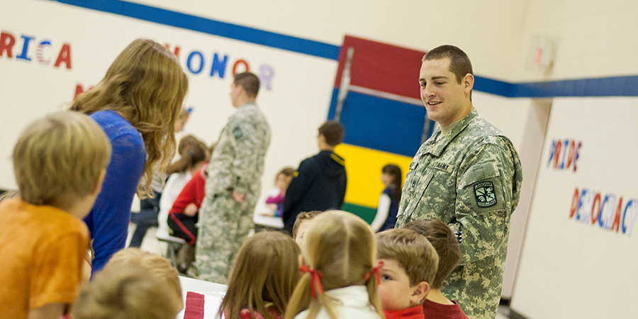 Man in a military uniform sits with children.