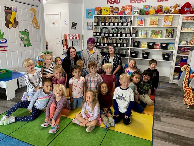 Three Future Teachers Association members pose with a class of preschool students.