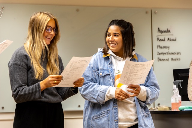 MBA lecture at Black Hills State University—professor explains an economics graph on the whiteboard as two students participate.