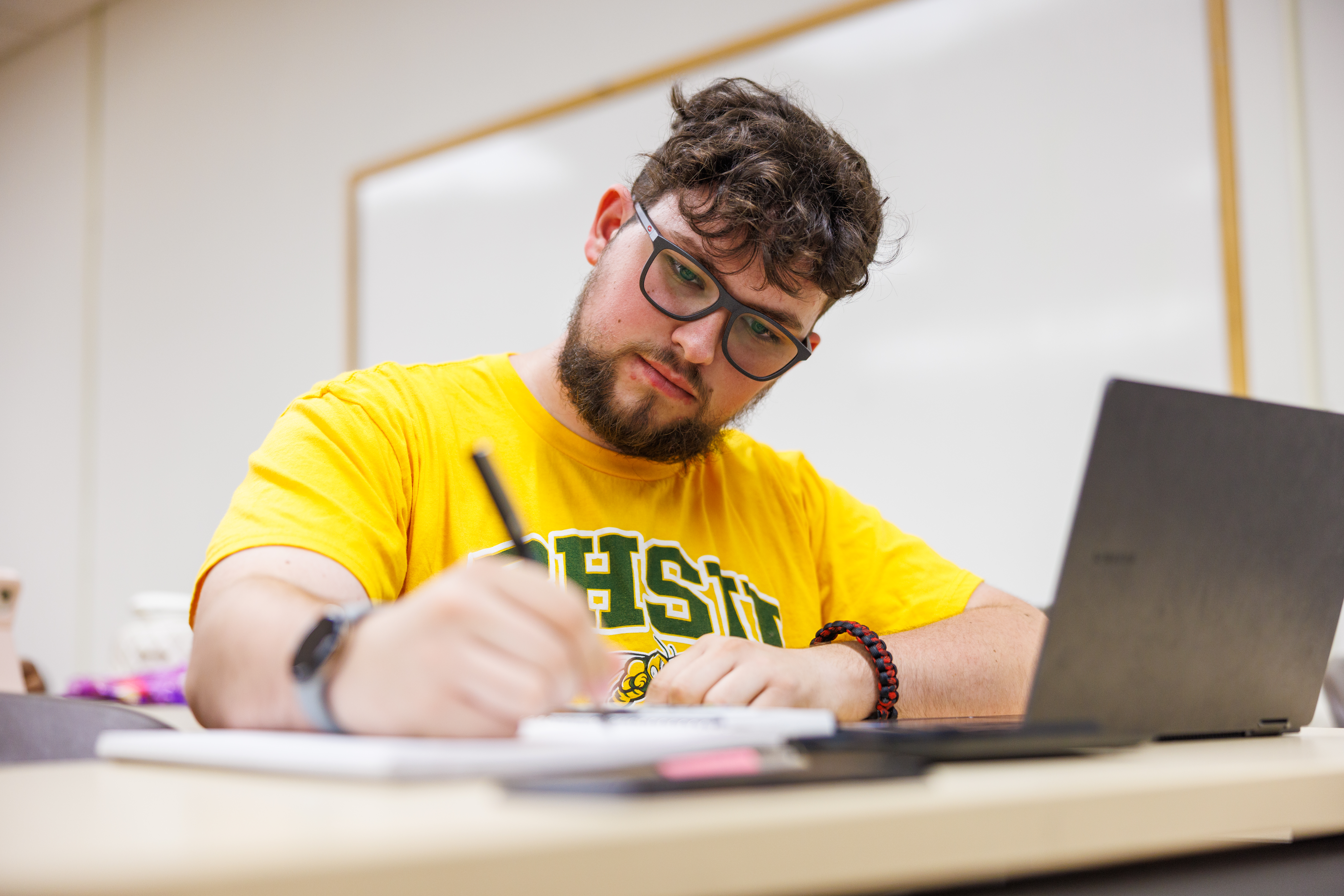 A BHSU student takes notes in class.