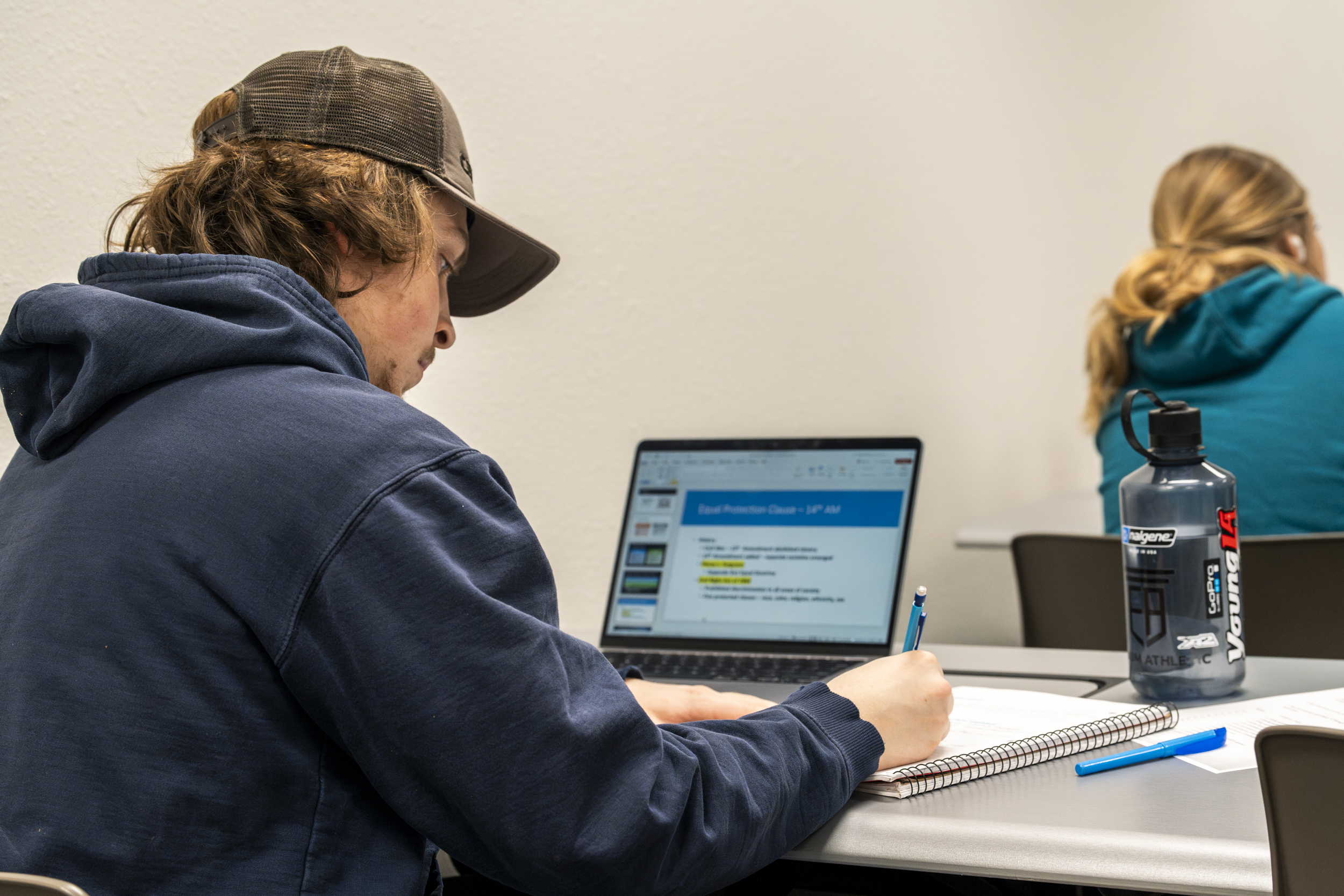 A BHSU student takes notes in class.