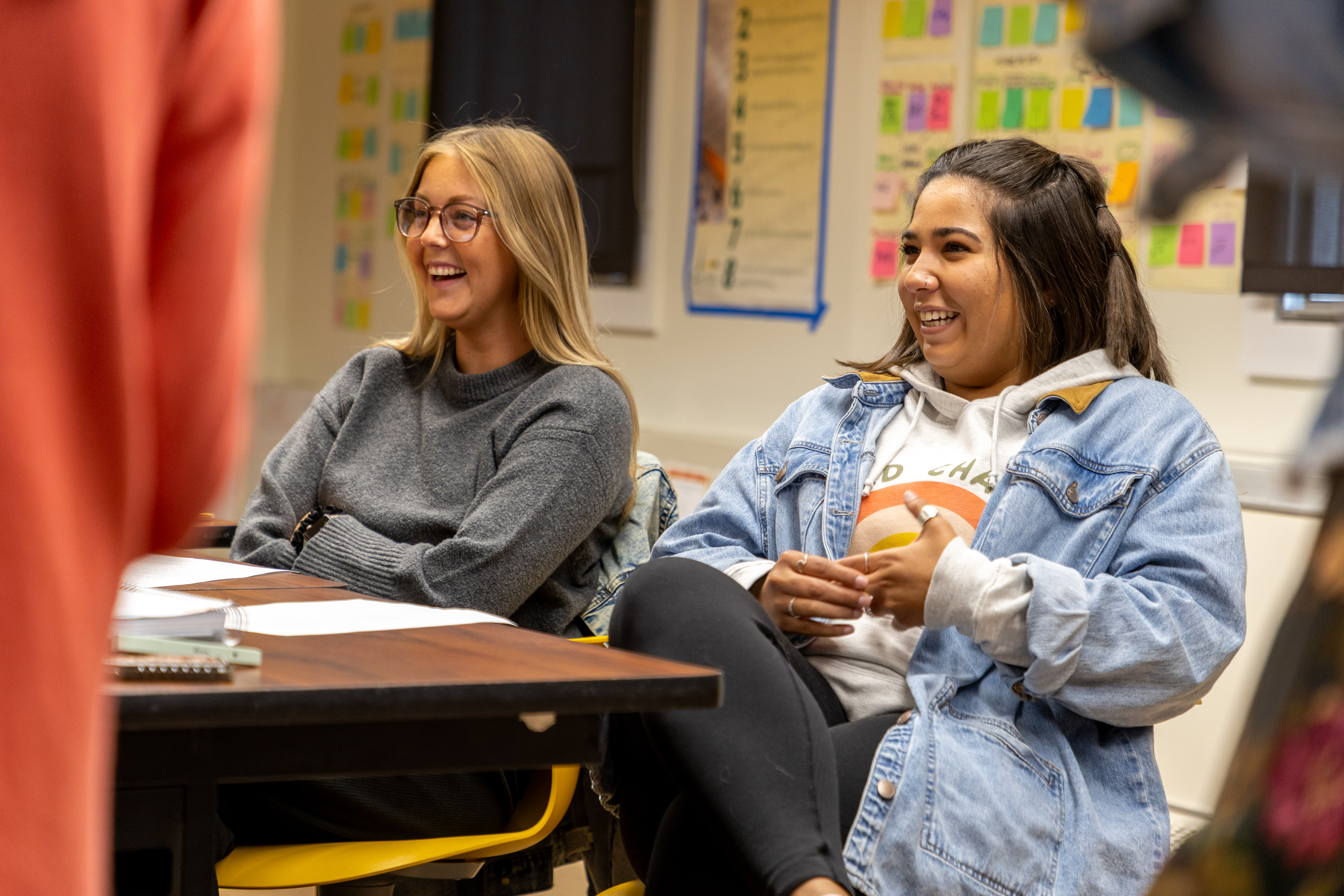 Two female BHSU education students sit in class smiling.