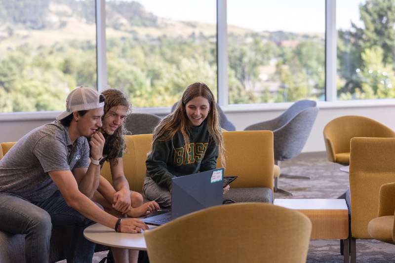 Three BHSU students work together on a project in the library.