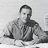 Black and white image of a man sitting at a desk.
