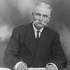 Black and white image of William J. Collins signing a paper.