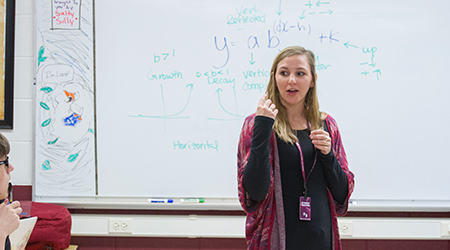 A woman stands in front of a whiteboard. 