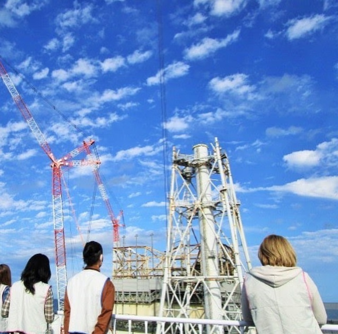 Three people with backs facing the camera, look at large machinery