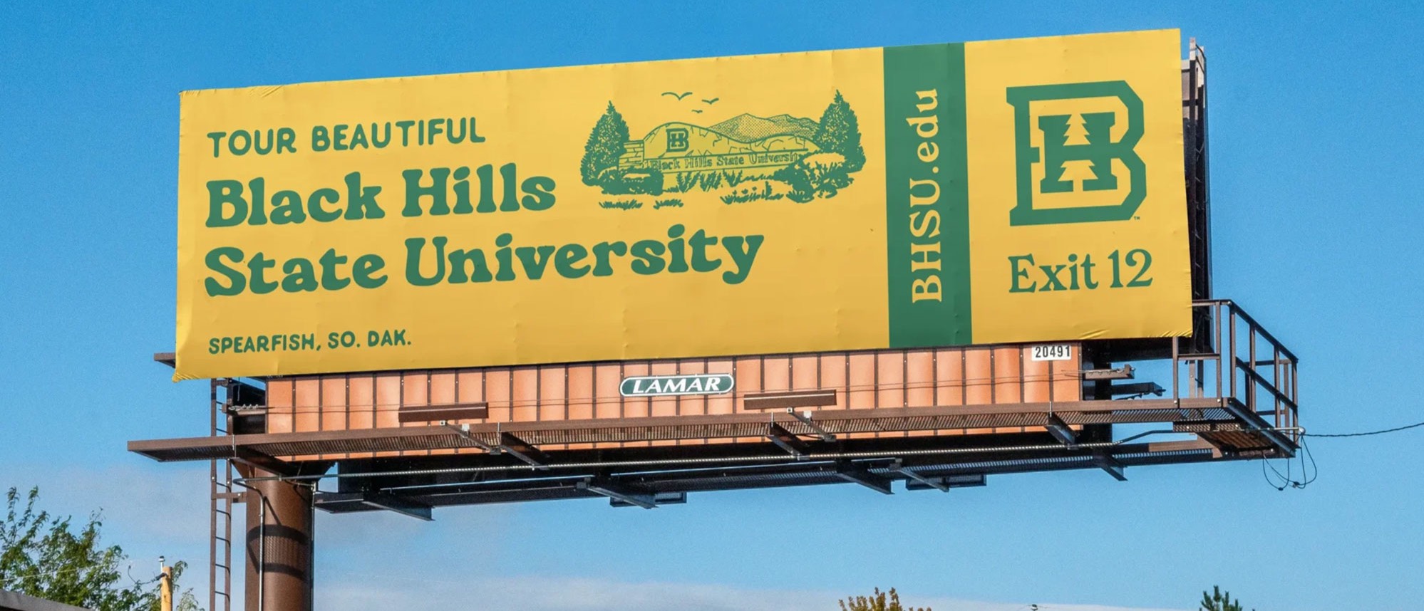 Image of a BHSU billboard. It is bright yellow with green text that says 
