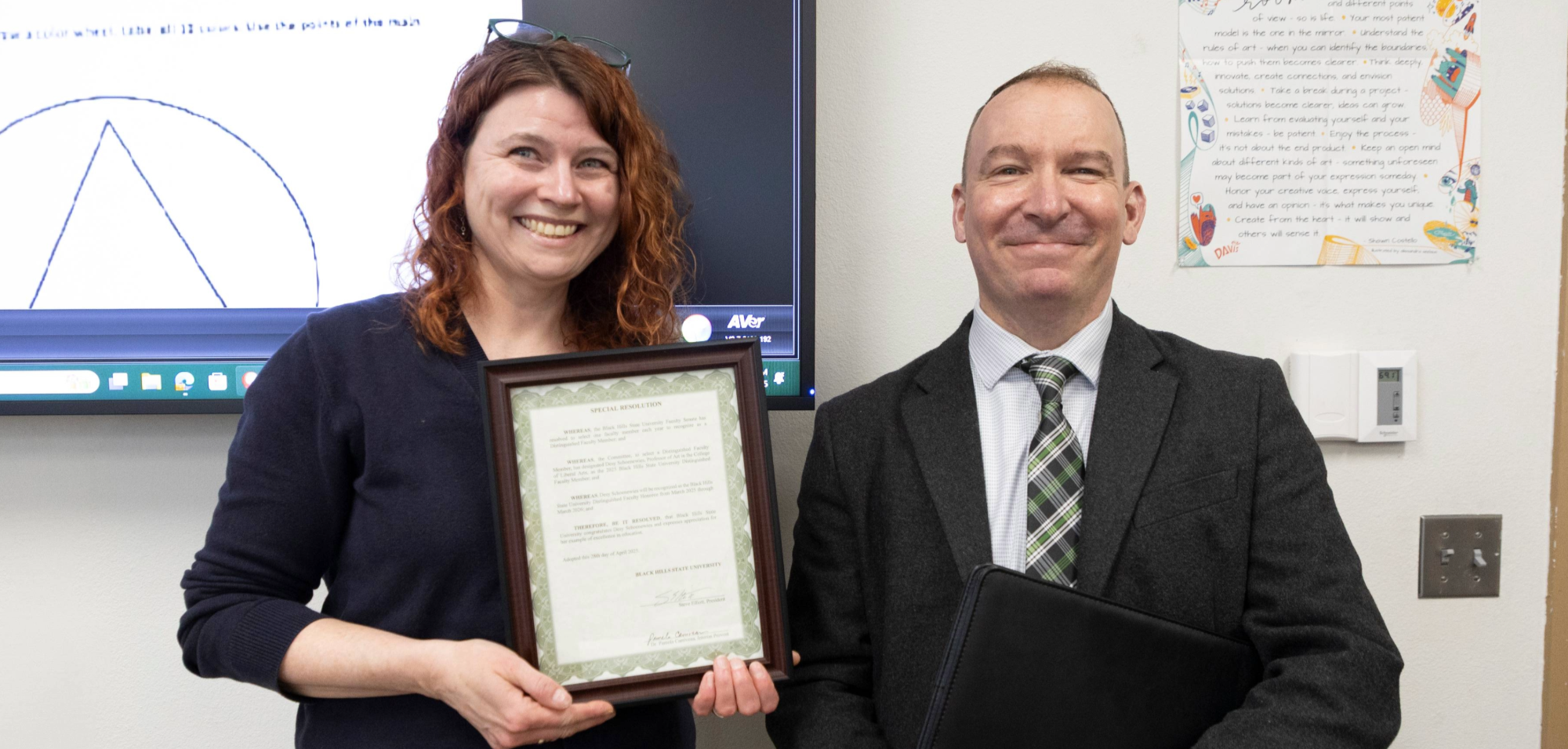 Image of Desy Schoenewies holding the distinguished faculty award and standing next to Steve Elliot