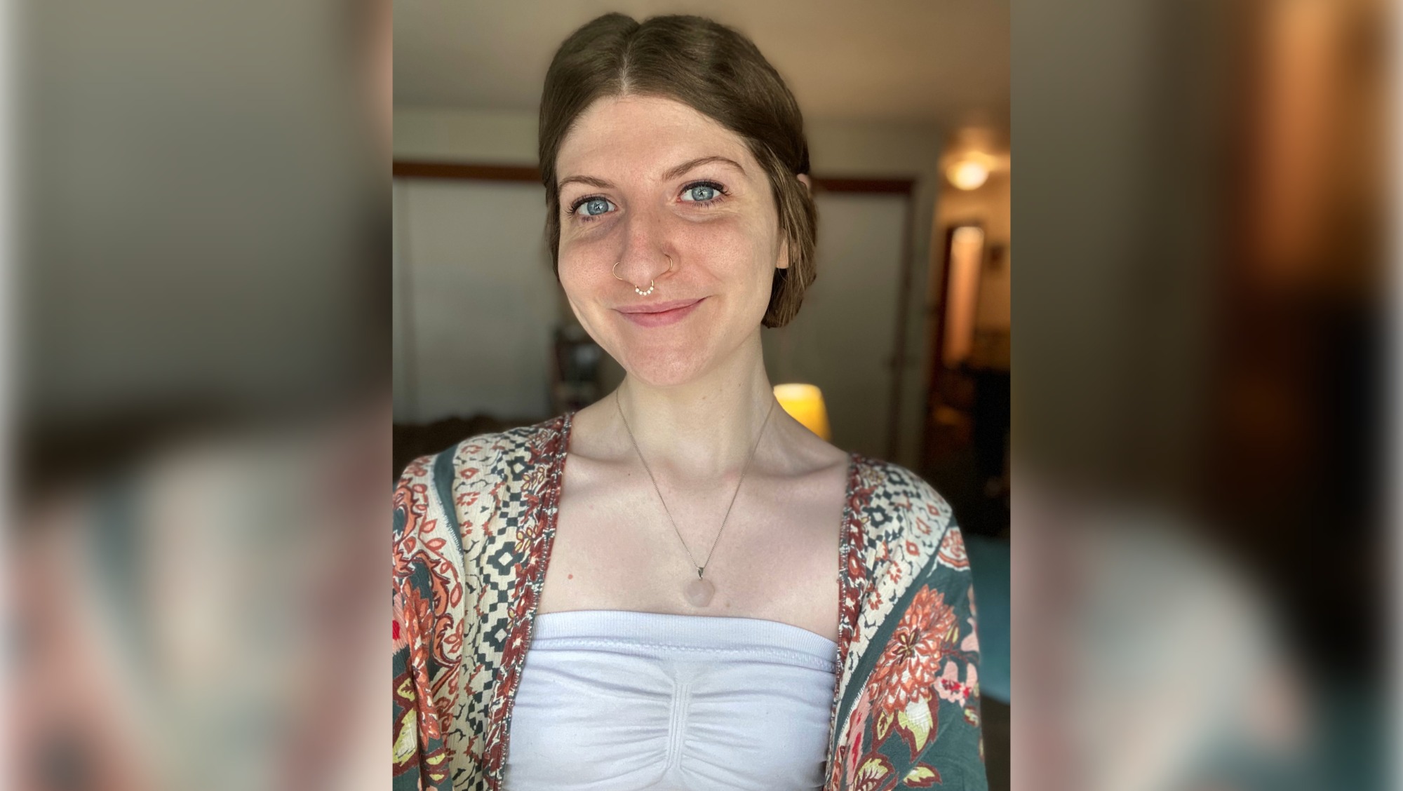 Photo shows a freckled woman with brown hair and blue eyes.