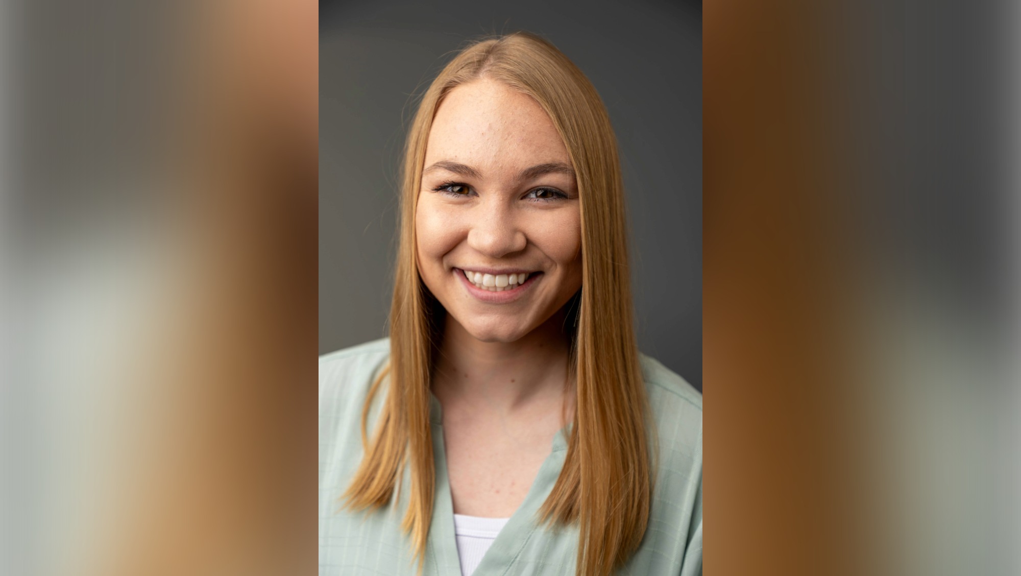 A woman with blond hair and brown eyes smiles as she looks into the camera.