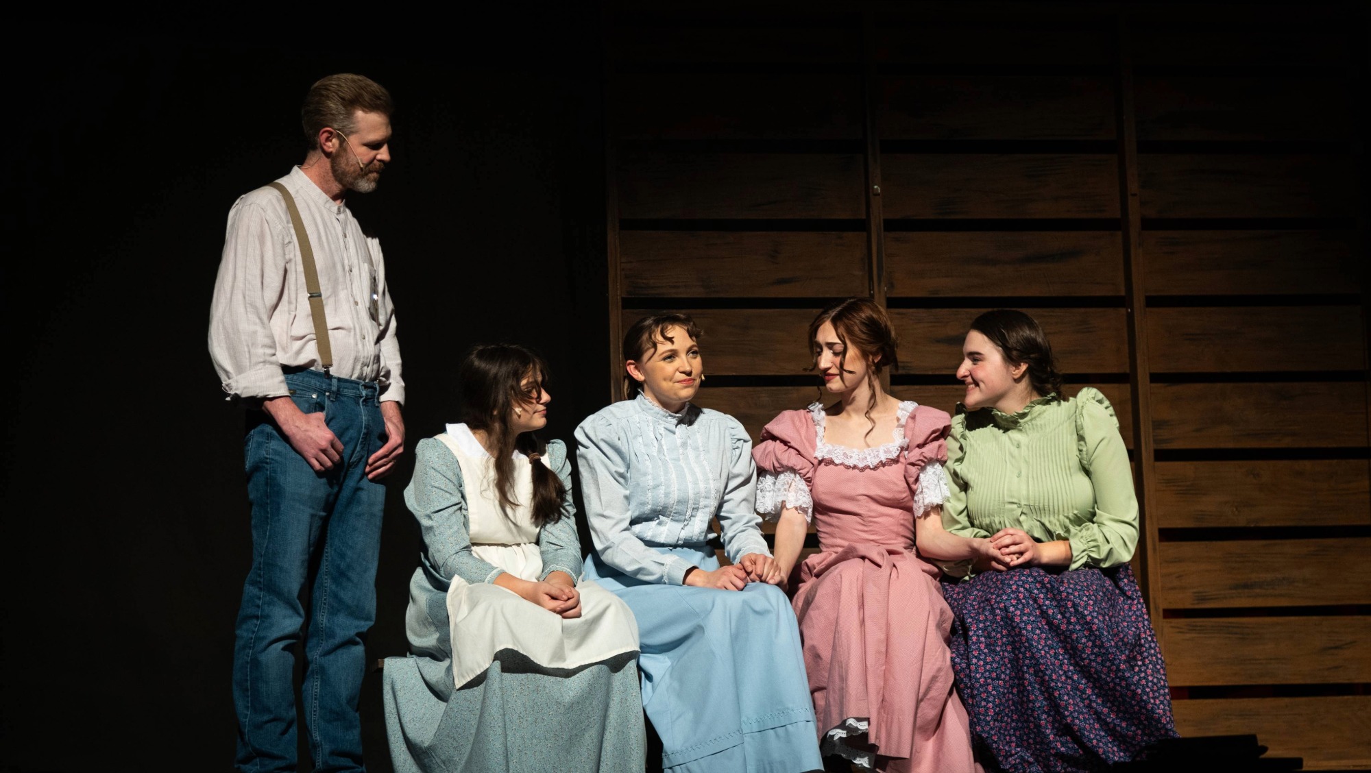 A cast for a musical sits on stage during a performance. 