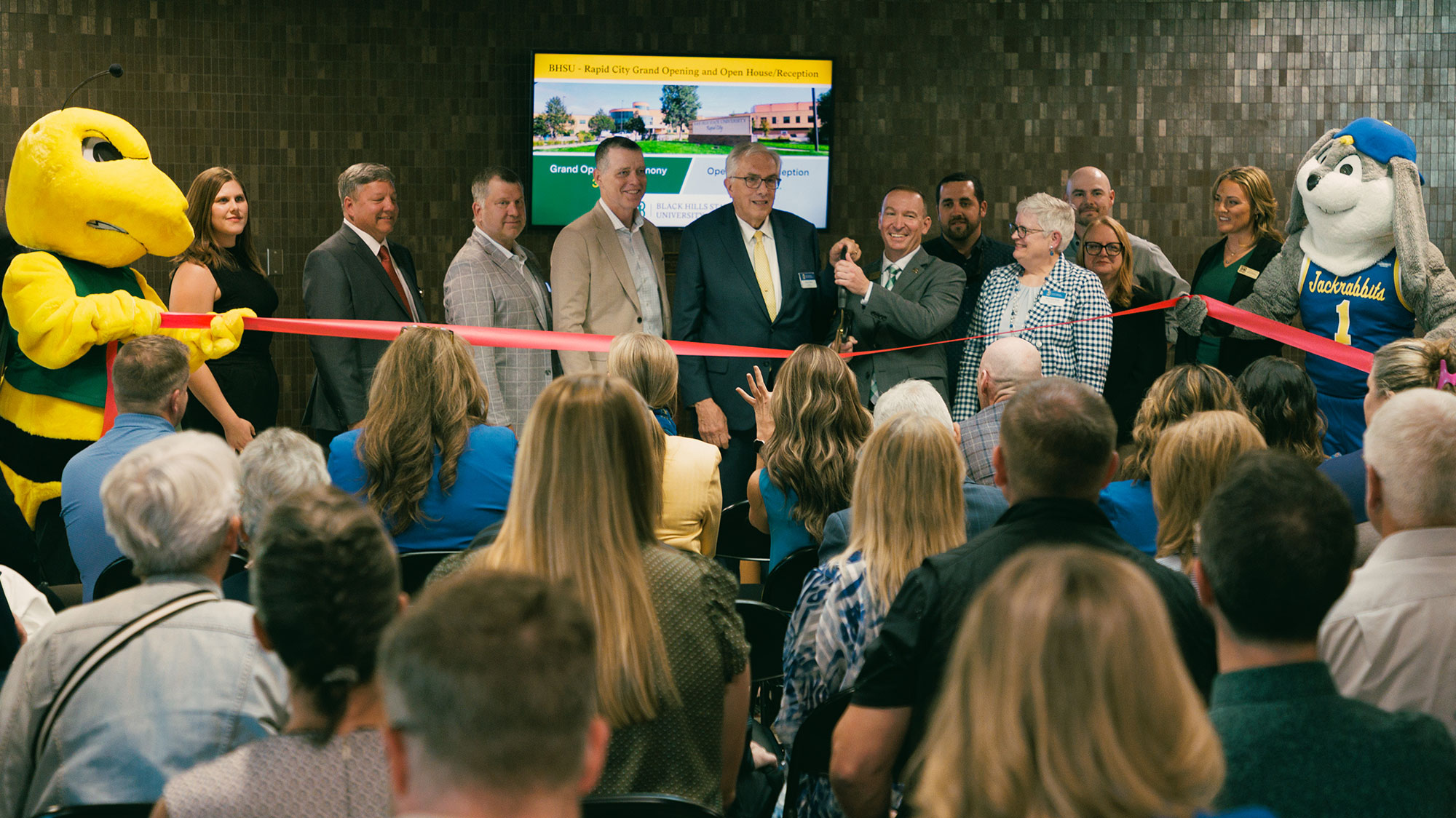 A ribbon-cutting ceremony was held to celebrate the grand opening of the Black Hills State University-Rapid City addition and renovation Tuesday, September 30. Pictured from left: BHSU Mascot Sting, Amanda Golemba, Alan Solano, Tim Rave, Nathan Lukkes, SDSU President Barry H. Dunn, BHSU President Steve Elliott, Bob Wessel, Dr. Mary Anne Krogh, Chris Maks, Dr. Pam Carriveau, Dr. Ashley Armstrong, SDSU Mascot Jack.