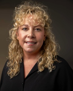 A woman with curly blonde hair smiles